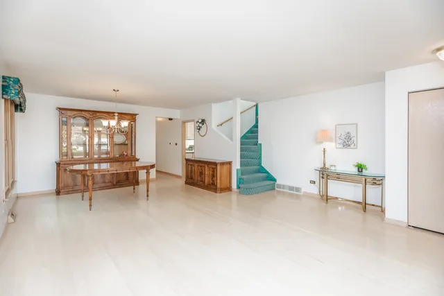 a living room with furniture and a dining table with projector the kitchen