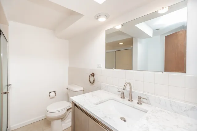 a bathroom with a sink vanity mirror and toilet