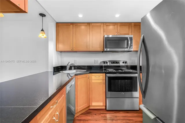 a kitchen with stainless steel appliances granite countertop a refrigerator a sink and a stove