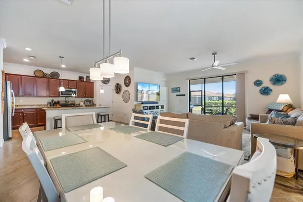 a living room with stainless steel appliances furniture a rug and a kitchen view