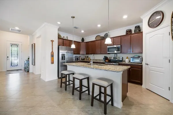 a kitchen with stainless steel appliances granite countertop a refrigerator a oven a sink a dining table and chairs