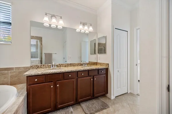 a spacious bathroom with a granite countertop double vanity sink a mirror and a bathtub