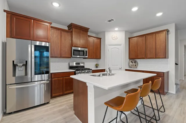 a kitchen with stainless steel appliances a stove refrigerator sink and wooden cabinets
