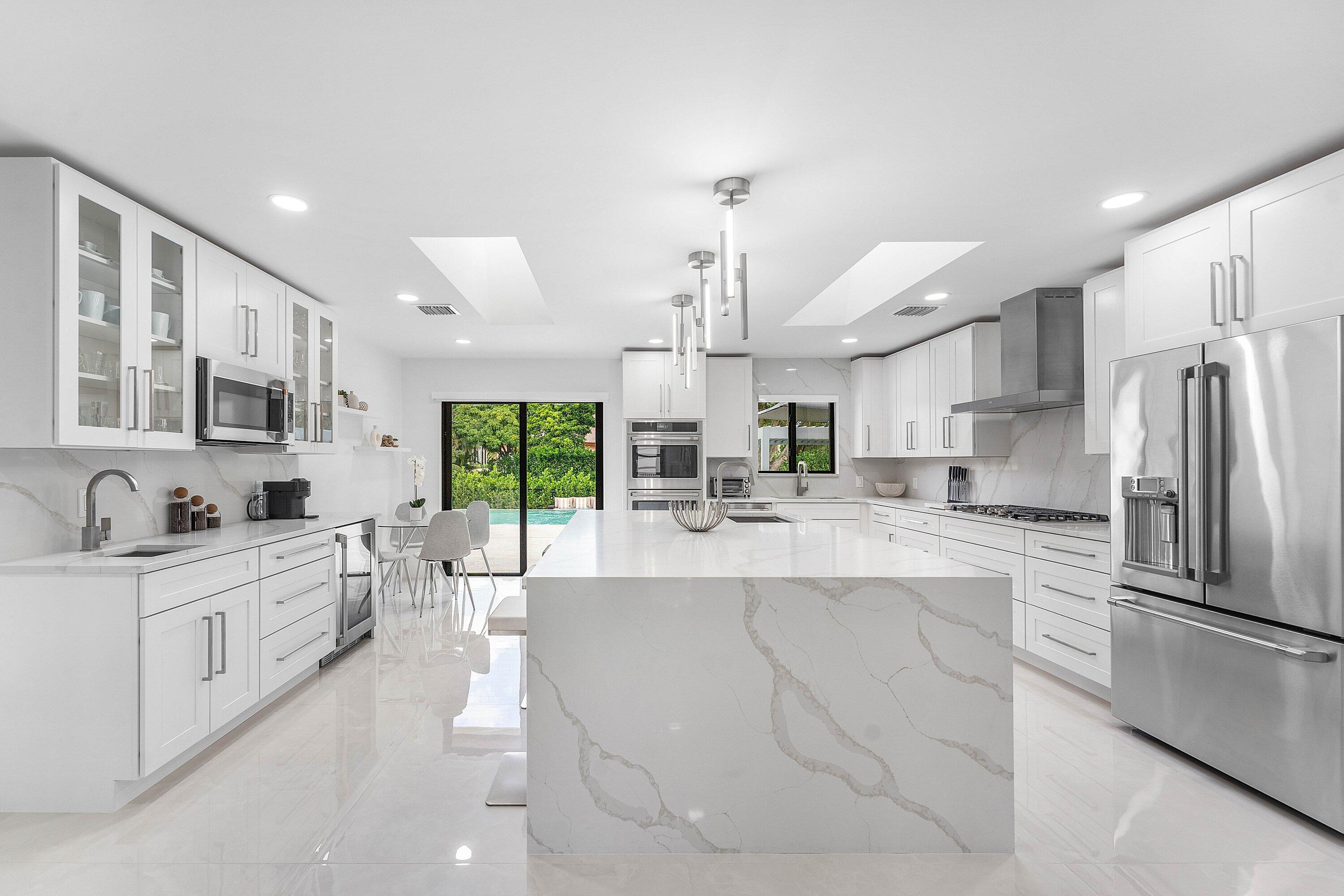 8274 Sawpine Road Delray Beach, FL 33446 - Photo 13 of 63 a large kitchen with kitchen island a large counter top space a sink stainless steel appliances and cabinets