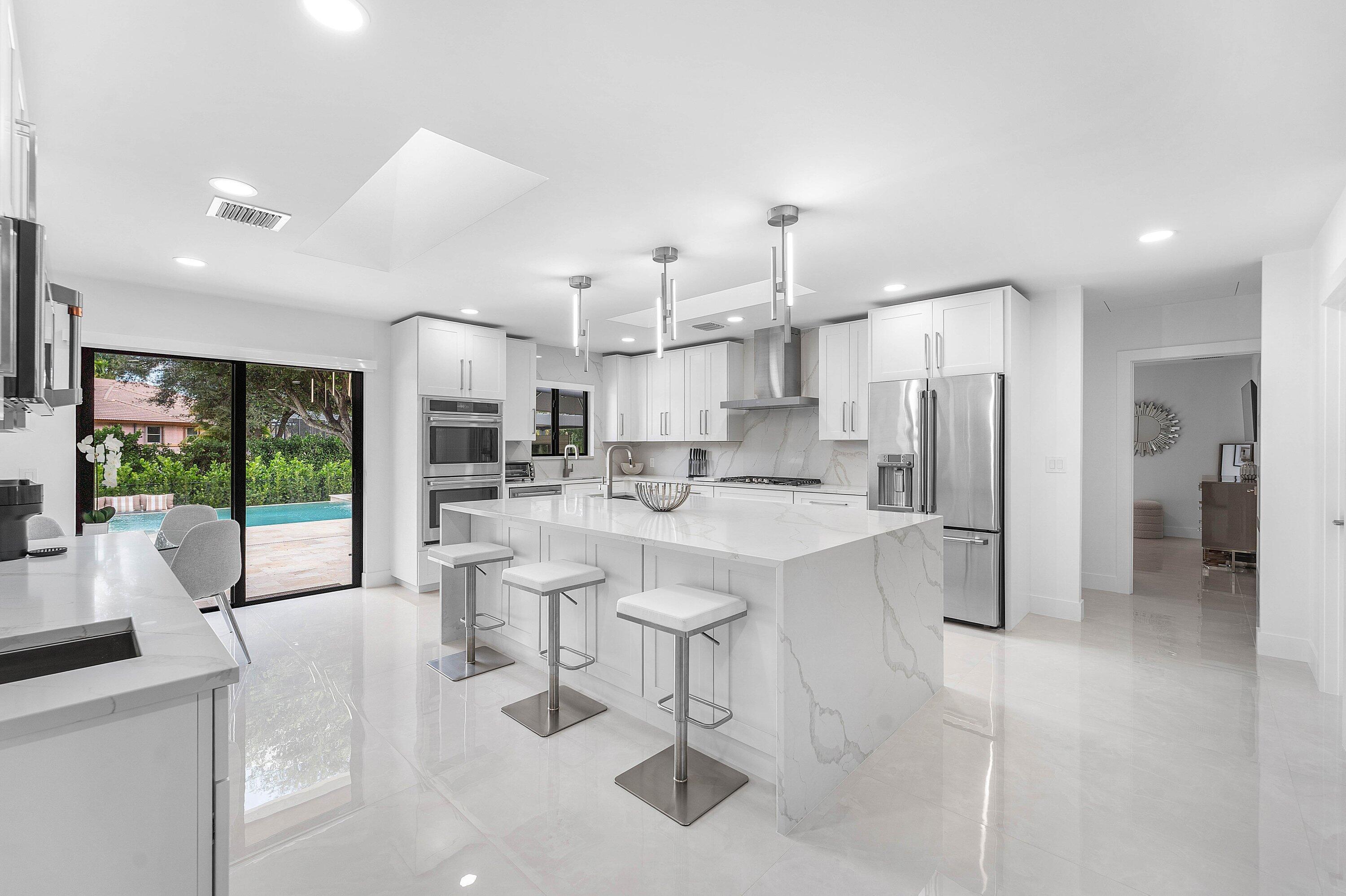 8274 Sawpine Road Delray Beach, FL 33446 - Photo 14 of 63 a large white kitchen with a large window and stainless steel appliances