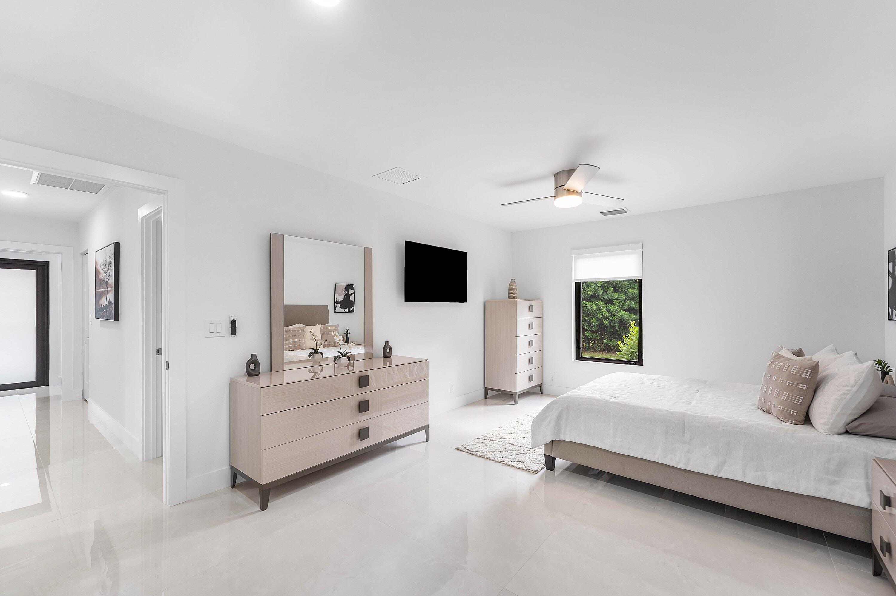 8274 Sawpine Road Delray Beach, FL 33446 - Photo 26 of 63 a spacious bedroom with a bed and a flat screen tv