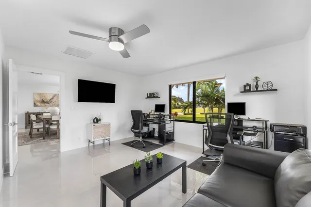a view of a white house with a big yard and potted plants and trees
