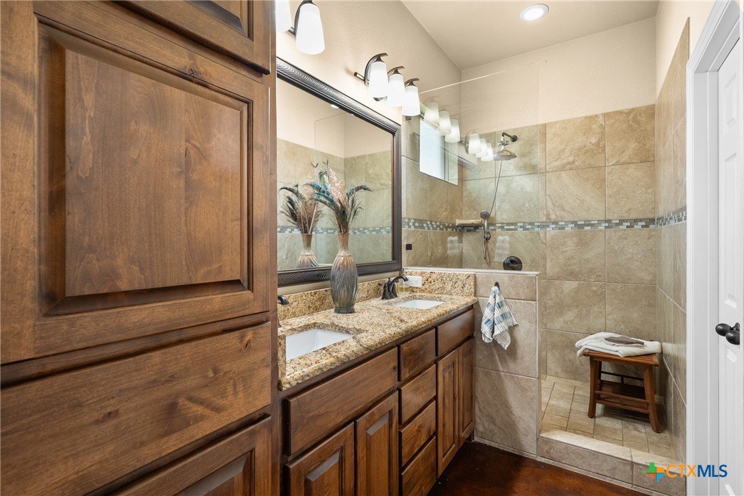 2405 Twin Ridge Court Belton, TX 76513 - Photo 23 of 30 a bathroom with a granite countertop sink a mirror and a shower