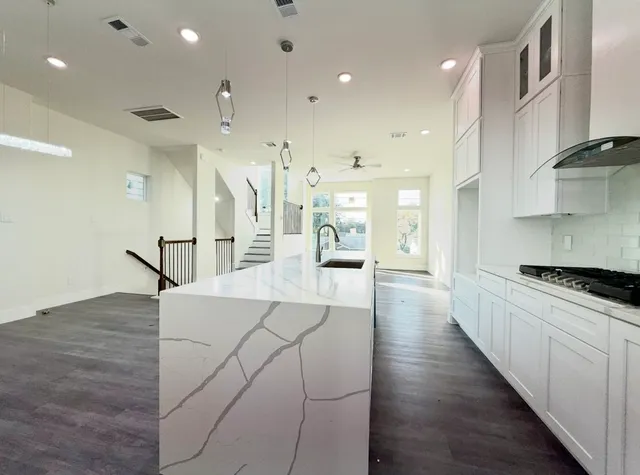 a large kitchen with stainless steel appliances kitchen island a large counter top and a wooden floors