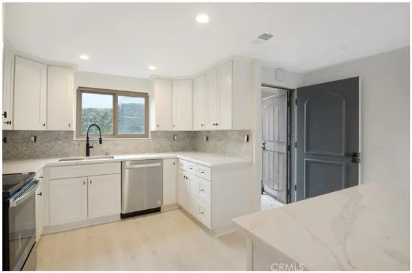 a kitchen with white cabinets and sink