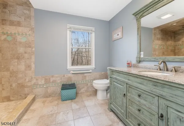a bathroom with a granite countertop sink a toilet and a mirror