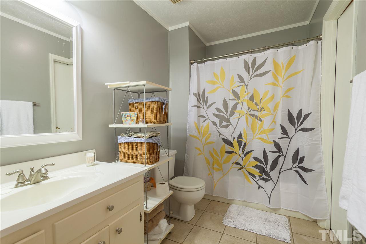 919 Grovemont Road Raleigh, NC 27603 - Photo 15 of 24 a bathroom with a granite countertop sink a toilet and a shower curtain