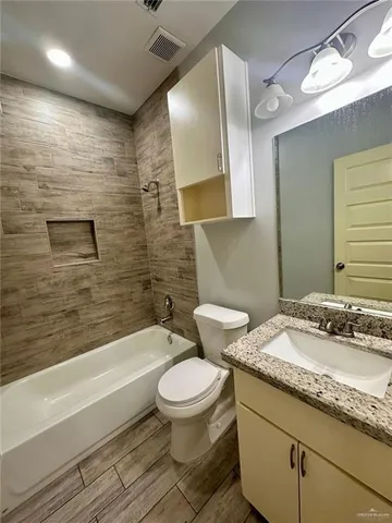 a bathroom with a granite countertop toilet a sink and bathtub
