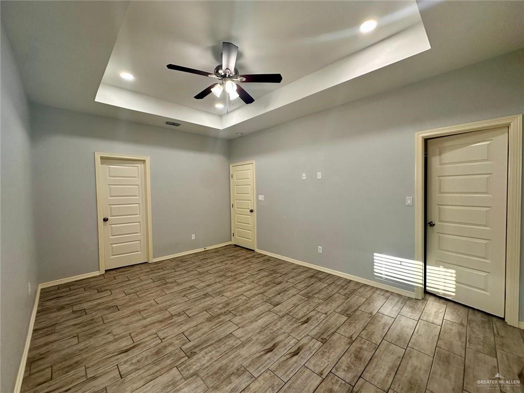 1503 West Heritage Drive, Unit 1 Pharr, TX 78577 - Photo 13 of 17 Empty room featuring a tray ceiling, wood finish floors, ceiling fan, and recessed lighting