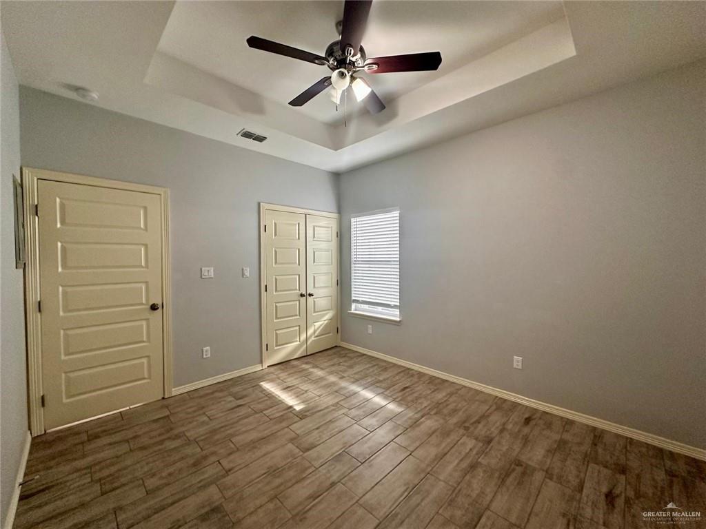 1503 West Heritage Drive, Unit 1 Pharr, TX 78577 - Photo 10 of 17 Unfurnished bedroom featuring a raised ceiling, dark wood-style floors, a ceiling fan, and a closet