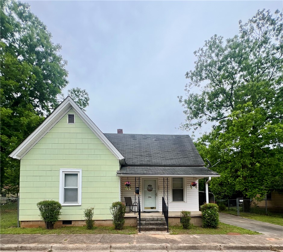204 G Street Anderson, SC 29625 - Photo 1 of 8 A charming cottage facade awaits, nestled among mature trees on a quiet street.