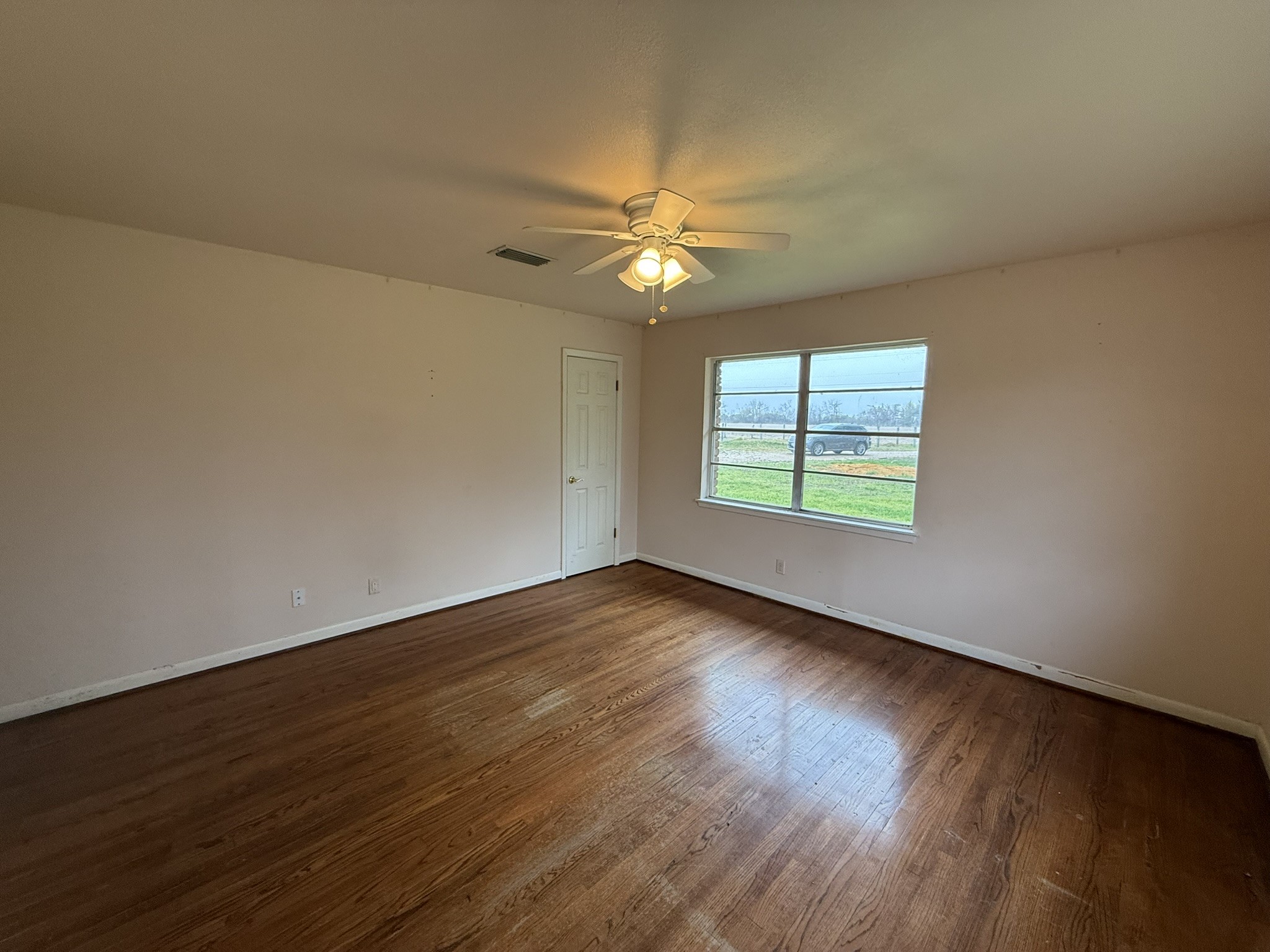 13907 Mueck Road Needville, TX 77461 - Photo 22 of 27 an empty room with wooden floor ceiling fan and windows