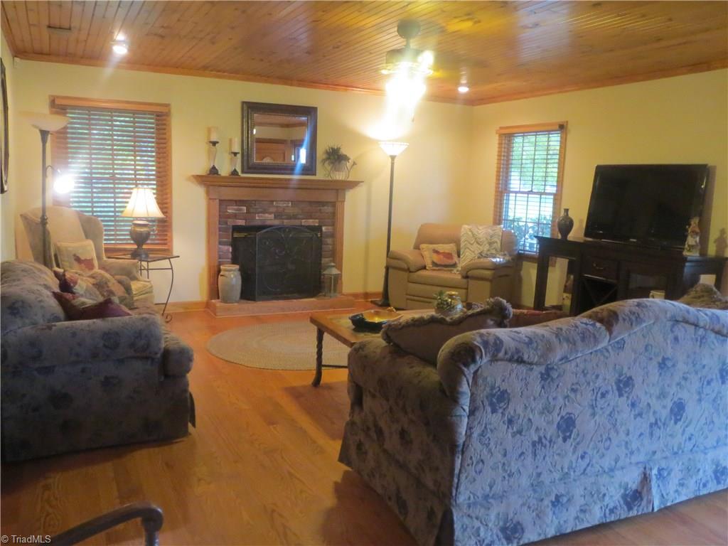 953 Hodges Mill Road Dobson, NC 27017 - Photo 9 of 29 Living room with brick fireplace, bead board ceiling and hardwood floors.