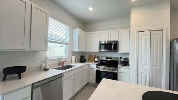 a kitchen with stainless steel appliances a sink a stove a microwave a refrigerator a sink and cabinets