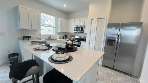 a kitchen with stainless steel appliances a table chairs and a refrigerator