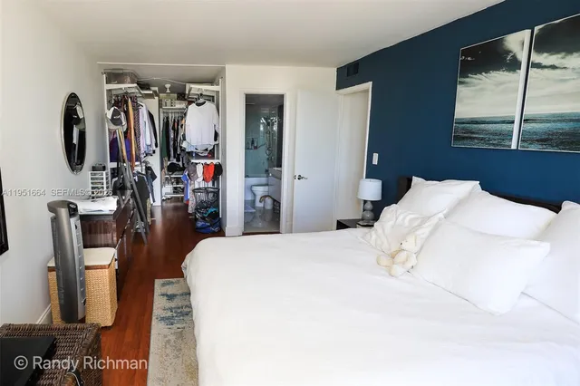 a bedroom with a bed a large window and walk in closet