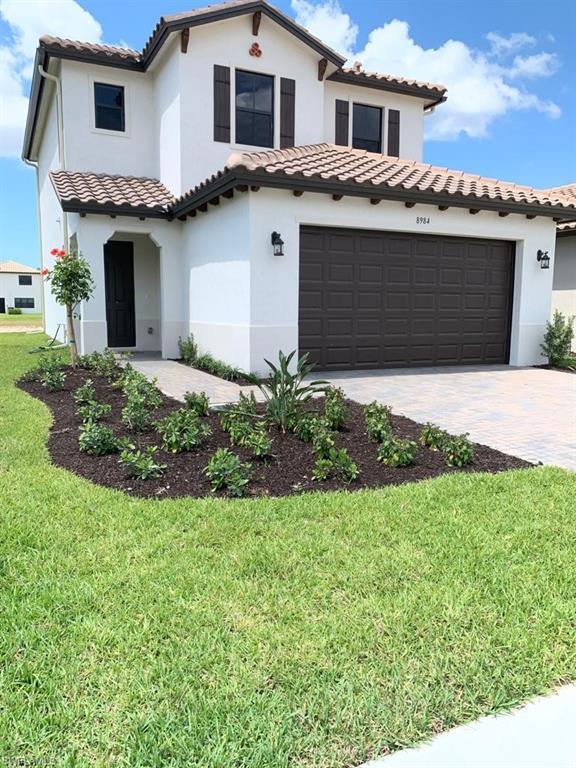 8984 Madrid Circle Naples, FL 34104 - Photo 1 of 15 a front view of a house with a garden and plants