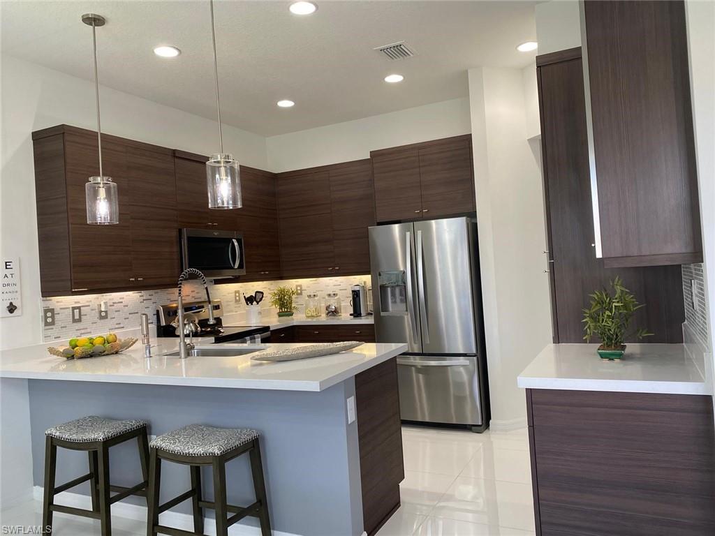 8984 Madrid Circle Naples, FL 34104 - Photo 10 of 15 a kitchen with stainless steel appliances a sink cabinets and refrigerator