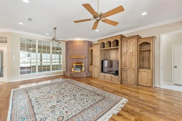 a view of a livingroom with a flat screen tv wooden floor and a ceiling fan