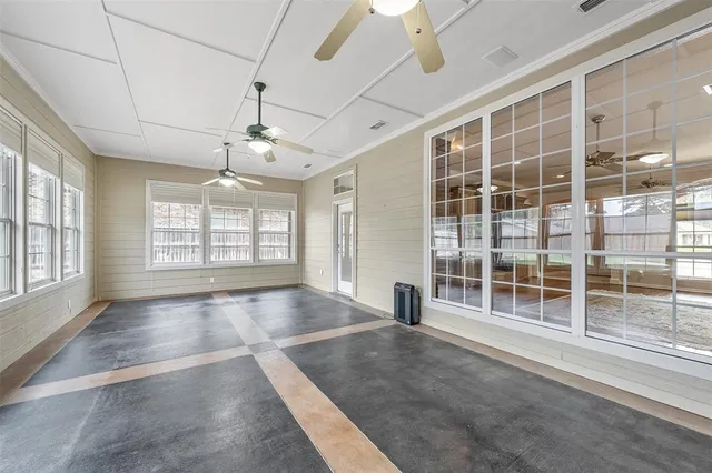 a view of an empty room with a window and chandelier fan