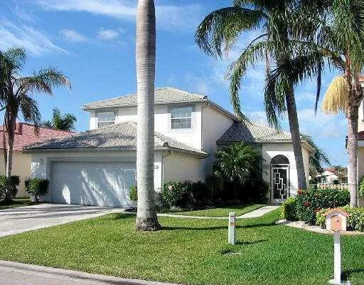 a view of a house with a yard and palm trees