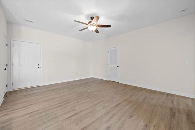 an empty room with wooden floor and windows