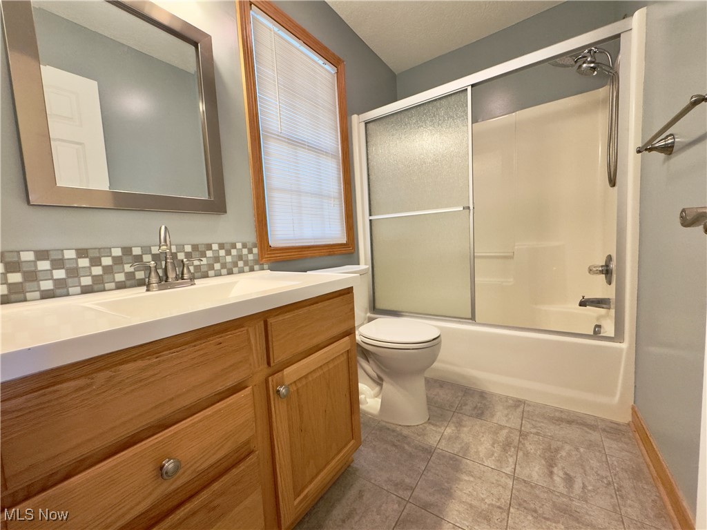 6014 Wentworth Road Southwest Canton, OH 44706 - Photo 17 of 22 Full bath featuring bath / shower combo with glass door, vanity, light tile patterned floors, and tasteful backsplash