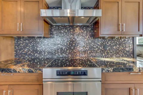 a kitchen with stainless steel appliances granite countertop a stove a sink dishwasher and a refrigerator with wooden floor