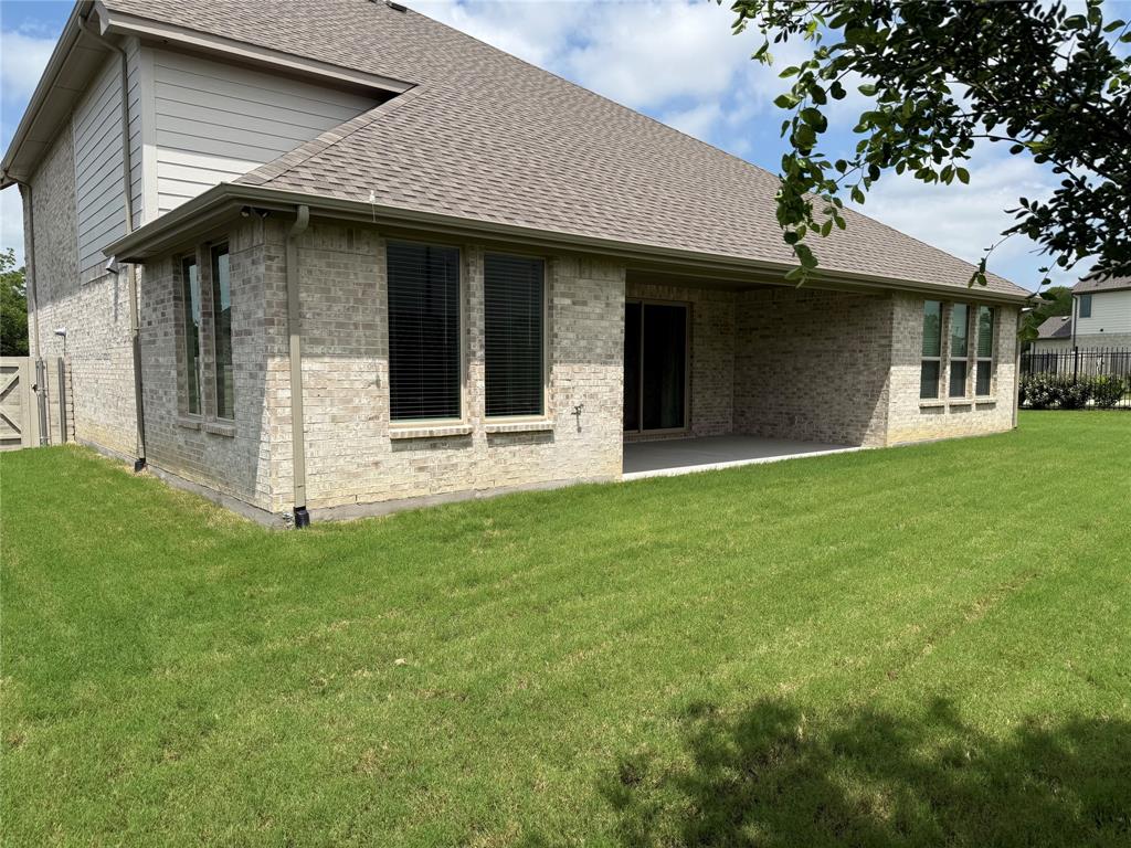 2708 Andesite Road McKinney, TX 75071 - Photo 4 of 35 Expansive green lawn surrounds a property featuring light-colored brick siding and a covered patio area