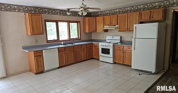 a kitchen with stainless steel appliances granite countertop a refrigerator a sink a stove and white cabinets