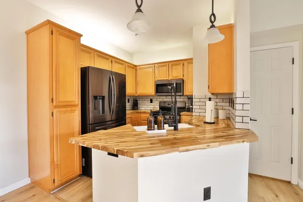 a kitchen with kitchen island granite countertop a sink appliances cabinets and furniture