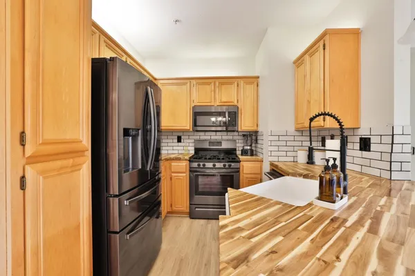 a kitchen with stainless steel appliances granite countertop a refrigerator a stove and a sink with cabinets