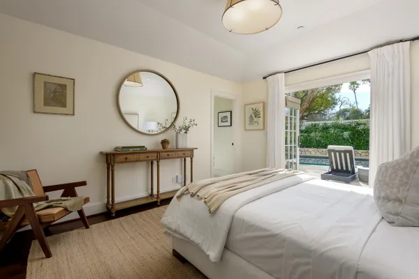 a bedroom with a bed a mirror and a large window