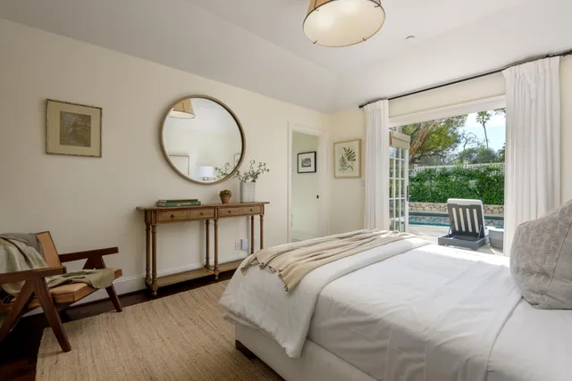 a bedroom with a bed a mirror and a large window