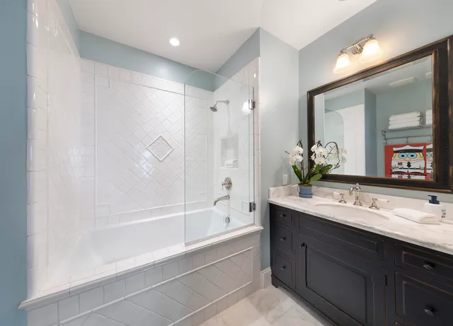a bathroom with a bathtub shower sink double vanity and mirror