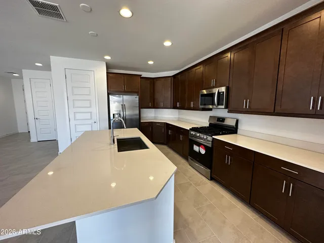 a kitchen with stainless steel appliances a sink a stove top oven a refrigerator and cabinets