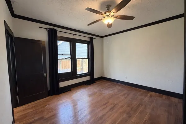 a view of an empty room with a window and wooden floor
