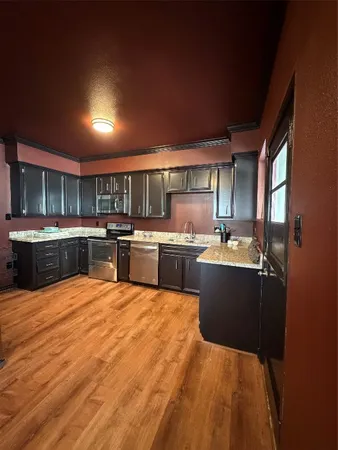 a large kitchen with kitchen island a sink a counter space stainless steel appliances and cabinets