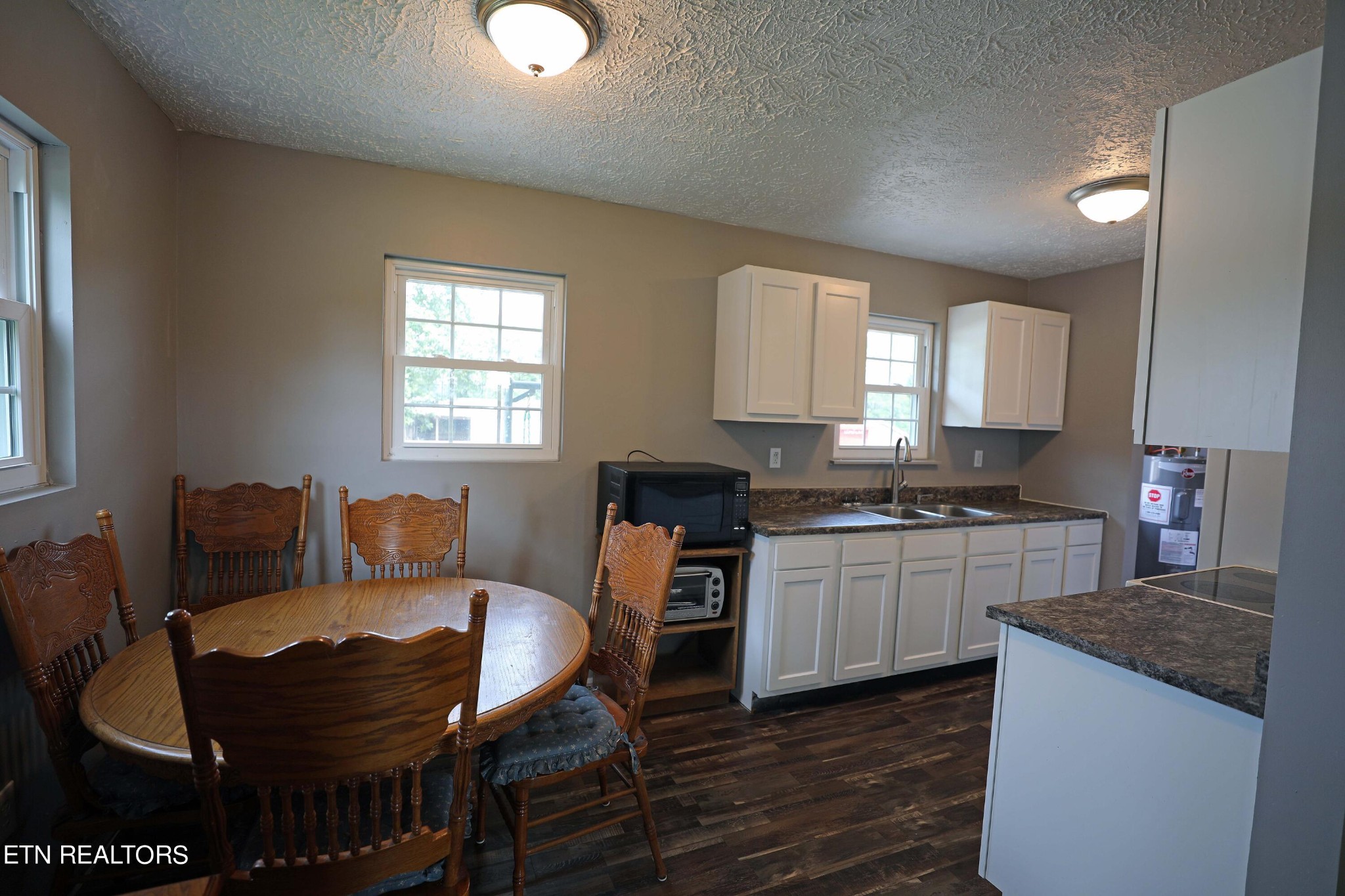 7816 Majors Road Corryton, TN 37721 - Photo 5 of 13 a kitchen with stainless steel appliances granite countertop a stove top oven a sink a dining table and chairs with wooden floor