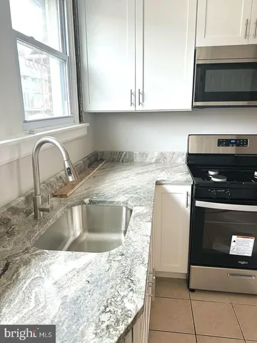 a kitchen with granite countertop a sink a stove and cabinets