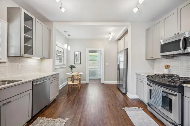 a kitchen with granite countertop a stove top oven a sink dishwasher a dining table and chairs with wooden floor