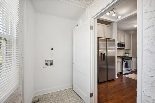 a view of a refrigerator in kitchen and an empty room