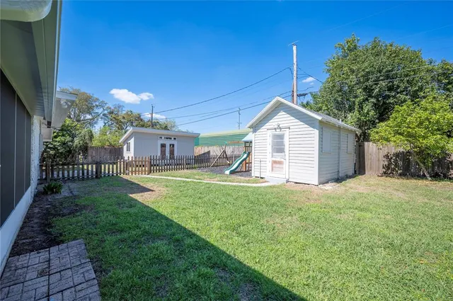 a view of backyard with small cabin and wooden fence