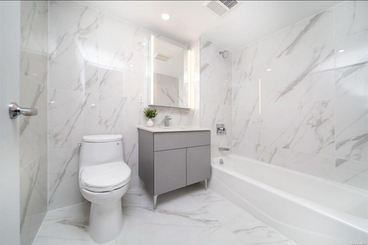 136-80 41st Avenue, Unit 7B Queens, NY 11355 - Photo 6 of 7 Full bath featuring bathtub / shower combination, vanity, visible vents, toilet, and marble finish floor