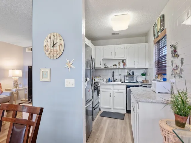 a kitchen with stainless steel appliances granite countertop a refrigerator a stove a sink and white cabinets